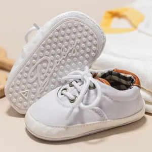 Detail of baby canvas shoes showing non-slip soles with grips and plaid lining