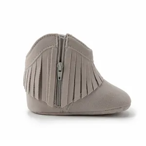 Detail of light gray suede baby boots with side zipper closure and soft fringe trim
