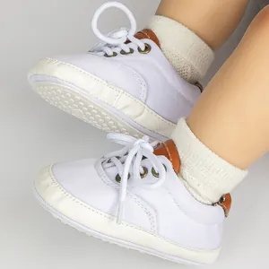 Detailed view of white canvas baby sneakers featuring gold eyelets and non-slip soles