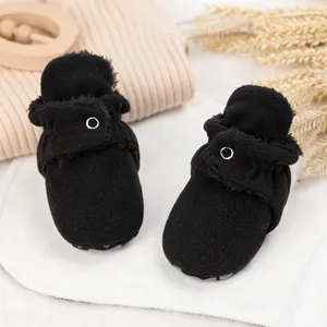 Nahaufnahme schwarzer Baby-Plüschschuhe mit grauen Anti-Rutsch-Noppen auf der Sohle