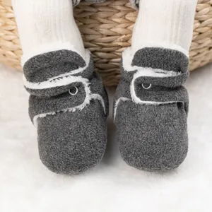 Nahaufnahme warmer dunkelgrauer Babyschuhe mit weißem Kunstfellfutter und Klettverschluss