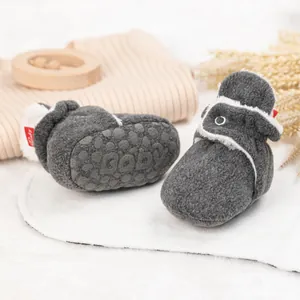 Nahaufnahme von weichem grauem Fleece-Babyschuh mit weißem Futter und rutschfester Sohle