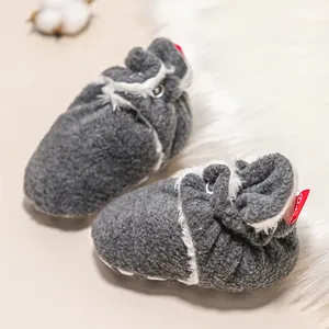 Detail von warmen Babyschuhen aus grauem Strick mit weißem Plüschfutter auf weichem Teppich