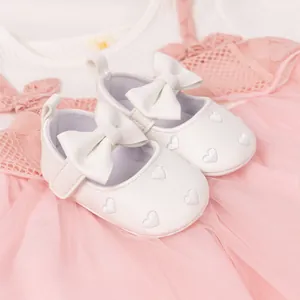 Detail of white leather baby princess shoes with a bow and silver heart embroidery