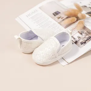 Detail of white sequin baby walking shoes with elastic opening on home magazine