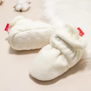 Nahaufnahme der rutschfesten Sohle und des Druckknopfs der warmen Babyschuhe
