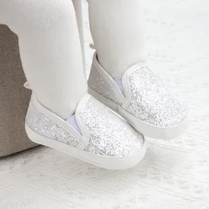Close-up of silver sequin baby walking shoes with soft soles and white trim