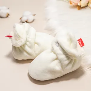 Detailaufnahme weißer Plüsch Babyhausschuh mit weichem Fleece und rotem Baby-Etikett