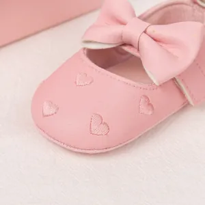 Detail of pink baby shoes showing soft leather texture and embroidered hearts with bow