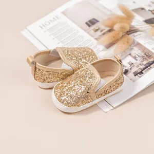 Macro shot of gold sequin infant walking shoes with elastic side and soft white soles
