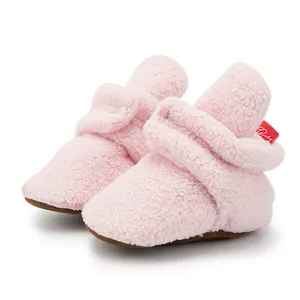 Close-up of pink fleece baby boots featuring a brown non-slip sole and Velcro closure
