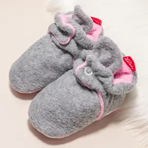 Nahaufnahme warmer grauer Baby-Hausschuhe mit rosa Plüschfutter und Knopf-Detail