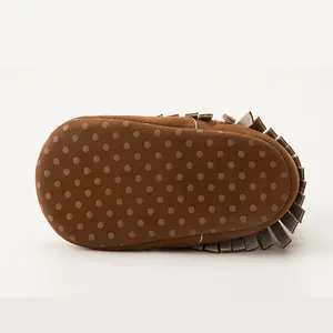 Close-up of brown baby moccasin with fringe and anti-slip dotted soft sole detail