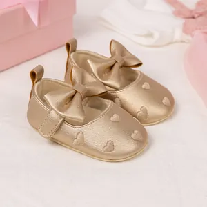Champagne gold baby Mary Jane shoes with embossed hearts and bow on a gift box