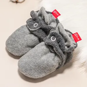 Detail von warmen grauen Baby-Plüschschuhen mit rotem 'Baby'-Etikett auf weichem Fleece