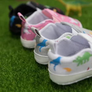 Weiche Baby Lauflernschuhe mit süßen Dino- und Einhorndrucken auf grünem Grasgrund