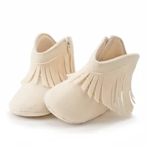 Detail of beige baby fringe boots featuring a side zipper closure and soft suede material