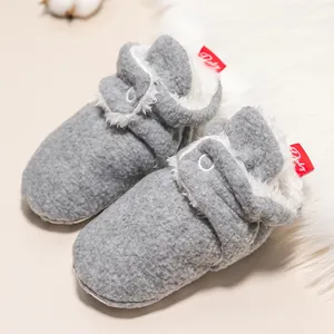 Detail von warmen grauen Babyschuhen mit weichem Fleecefutter und weißem Zierknopf