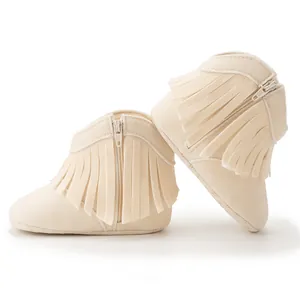 Close-up of off-white baby boots with soft suede texture, side fringe and silver zipper detail