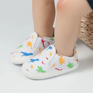 Detailansicht der Baby-Lauflernschuhe mit buntem Dinosaurier-Print auf weißem Canvas