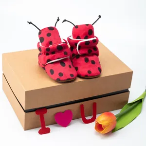 Close-up of ladybug-themed winter baby booties with soft red plush and Velcro straps