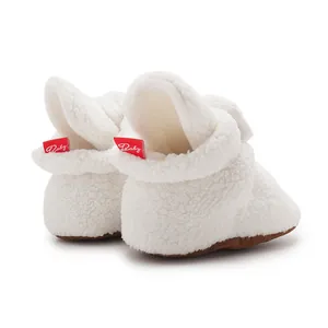 Detail of white plush baby shoe showing soft fuzzy texture and red 'Baby' heel label