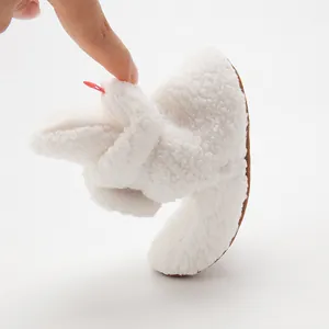 Flexible white sherpa baby shoes showing the soft bendable sole and plush texture