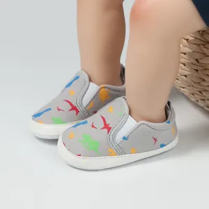 Detail von grauen Babyschuhen mit bunten Dinosauriermustern und elastischen Bändern
