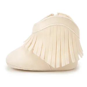 Detail view of cream fringe baby boots with soft soles and suede texture on white background