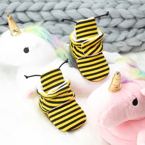 Detail of baby winter boots with yellow bee stripes and soft interior on plush rug