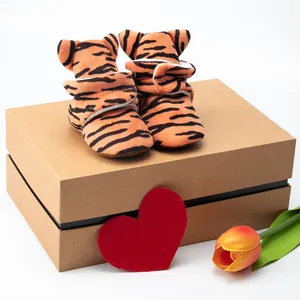 Close-up of baby tiger striped shoes with ear details on a gift box background