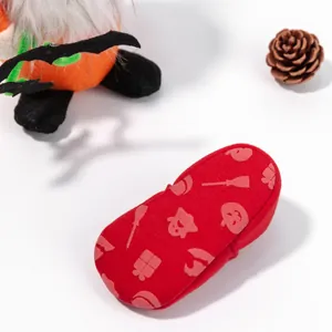 Red Halloween baby shoes with pumpkin and ghost patterns on white background with props