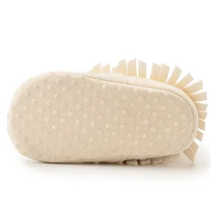Detail of soft baby walking shoe with non-slip silicone dots and fringe accents