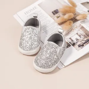 Macro detail of baby slip-on walking shoes featuring silver sequins and soft non-slip soles