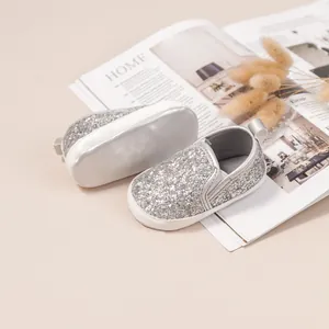 Macro view of silver glitter baby pre-walker shoes with soft sole and heel pull-loop