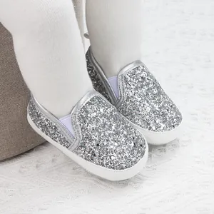 Detailed close-up of shiny silver sequined baby walking shoes with elastic straps