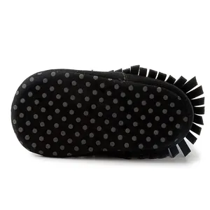 Close-up of black suede baby moccasin with fringe and non-slip dotted rubber sole