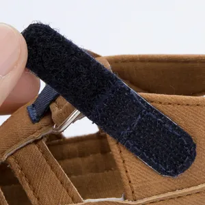 Details von braunen Babysandalen mit blauem Klettverschluss und Metall-D-Ring-Verschluss