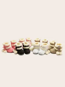 Détail de bottes de neige pour bébé avec doublure en fausse fourrure et boutons cœur à pompon
