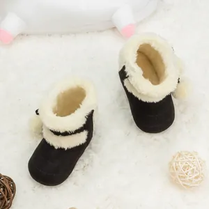 Détail de bottes de neige pour bébé avec doublure en peluche et pompons en noir