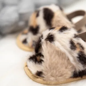 Gros plan de chaussons bébé en fausse fourrure léopard avec bride élastique au talon