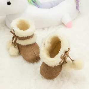 Bottes de neige pour bébé avec doublure en peluche et pompons blancs sur un tapis doux