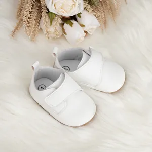 Chaussures souples blanches pour bébé avec velcro et semelle antidérapante sur tapis