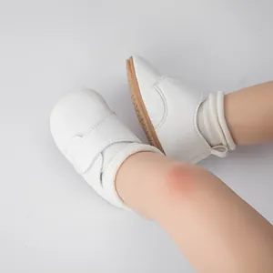 Gros plan de chaussures de bébé blanches à velcro et semelle antidérapante sur chaussettes