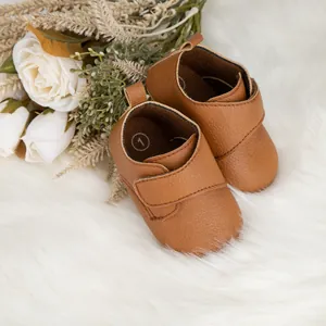 Chaussures de marche pour bébé en similicuir marron avec velcro sur tapis en peluche
