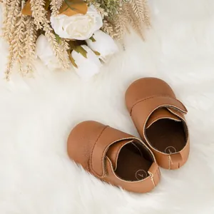Gros plan de chaussures de marche bébé marron avec velcro sur fausse fourrure blanche