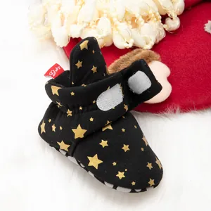 Détail de chaussures bébé noires à motifs étoiles dorées et fermeture velcro