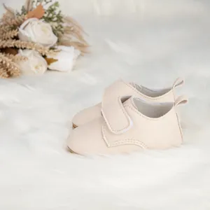 Gros plan de chaussures de marche bébé beiges à semelles souples sur tapis en peluche