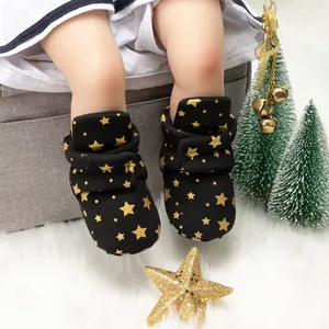 Gros plan de chaussures de Noël pour bébé avec étoiles dorées sur tapis en peluche