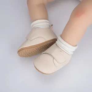 Gros plan sur chaussures bébé blanc cassé avec velcro et semelle en caoutchouc antidérapante